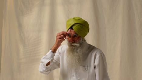 Fotografía-De-Estudio-De-Un-Hombre-Sikh-Mayor-Con-Barba-Que-Usa-Una-Aguja-De-Salai-Al-Ponerse-Un-Turbante-Contra-Un-Fondo-Liso-1